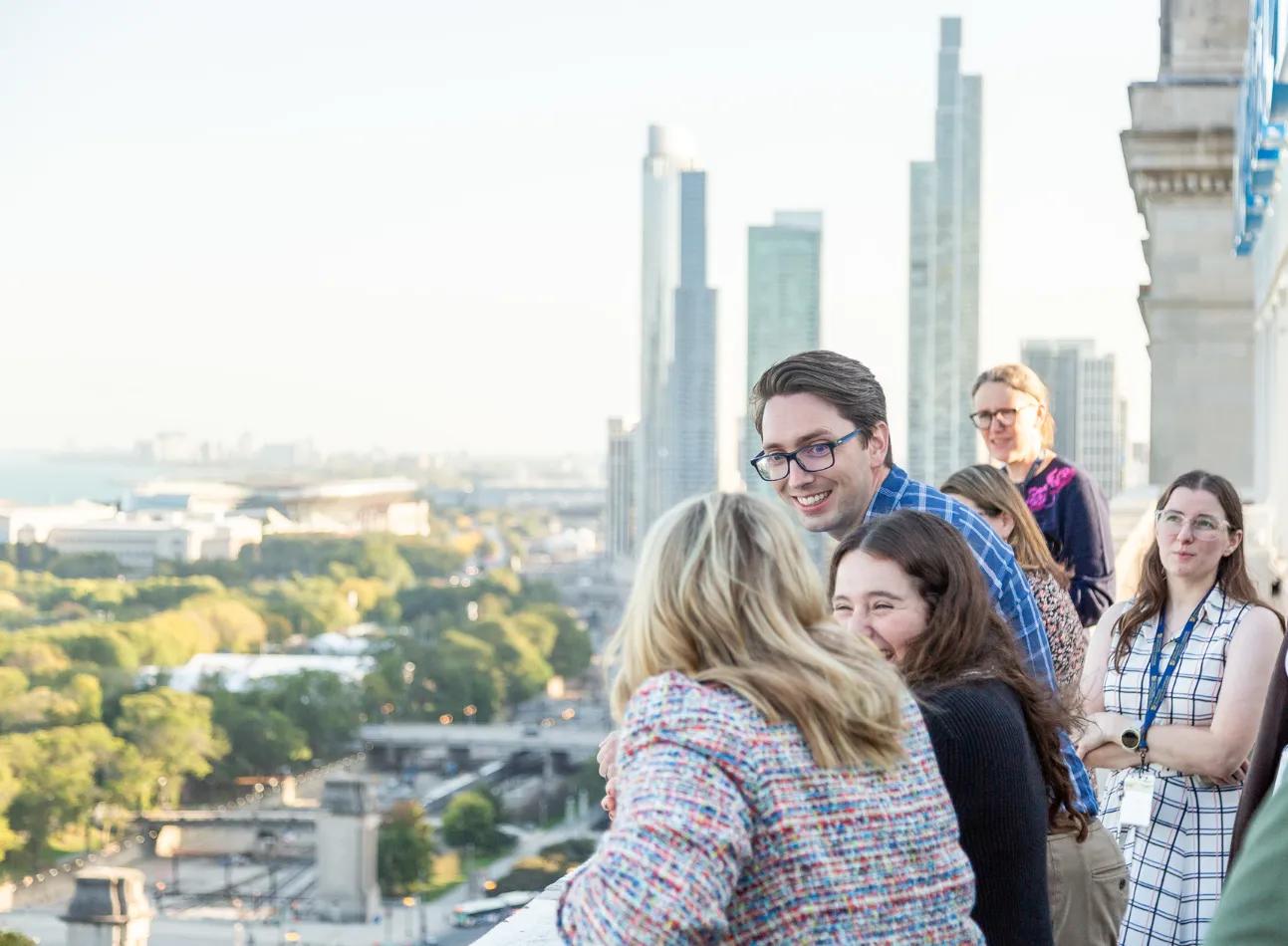 College students and faculty standing on balcony of high-rise, mid-discussion