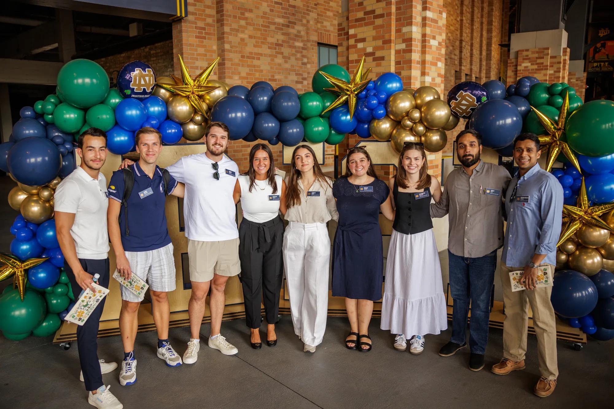 Group photo of MBA Class of 2025 Students attending orientation in front of Notre Dame balloon display in the concourse of the ND Football Stadium